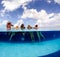 Half underwater split image of young women having fun in hotel pool in Caribbean sea. Concept of vacation and