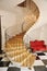 Hall with spiral staircase, glass chandelier and red sofa downstairs