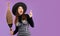 Halloweeen theme, young pretty asian woman in witch costume holding broom posing finger pointing on purple background