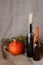 Halloween autumn still life. Pumpkin, candles in bottles, herbs. Light canvas background