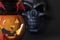 Halloween background. Glowing pumpkin and black skull on a dark background. Human fingers with long red claws