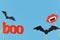 Halloween background with photo porps on sticks in shape of black bats, red word `boo` and vampire fang mouth on blue background