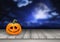 Halloween background with pumpkin on a wooden table against a spooky landscape