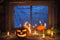 Halloween background, pumpkins and Jack-o ` - lantern next to burning candles on the background of an ominous night window