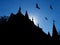 Halloween background with silhouettes of castle roofs with weathervanes and flying bats