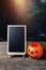 Halloween background. Spooky pumpkin, chalkboard on wooden floor