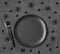 Halloween black table setting with spiders. Empty black plate, cutlery. spiders on dark gray background. Halloween festive serving