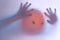 Halloween blurred background. A ghost resembling a pumpkin in color behind glass. Terrible and terrible nightmare