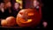 Halloween carved pumpkin on the table in front of a group of friends