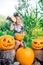 Halloween. Child dressed in black with jack-o-lantern in hand, trick or treat. Happy little girl pumpkin in the wood, outdoors.