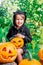 Halloween. Child dressed in black with jack-o-lantern in hand, trick or treat. Little girl pumpkin in the wood, outdoors.