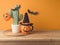 Halloween coffee cup and cactus decoration on wooden table over orange wall background