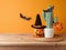 Halloween coffee cup and cactus decoration on wooden table over orange wall background. Holiday mock up for design and product