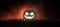 Halloween concept. Blurred silhouette of giant Jack-o-lantern pumpkin with scary smiling face behind crowd at night. People looks