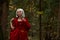 Halloween concept, glamorous costume detail. Young beautiful and mysterious woman in woods, in white Dress and Red Cloak