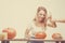 Halloween concept, happy Girl sitting at table with pumpkins preparing for holiday with candle and rope, cut Jack lantern, funny