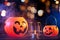 Halloween concept - Orange plastic pumpkin lantern on a dark wooden table with blurry sparkling light in the background, trick or