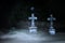 Halloween concept, stone crosses at night on the foggy cemetery