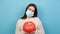 Halloween during coronavirus covid-19 pandemic quarantine concept. Portrait of young woman wearing medical mask hold pumpkin