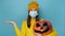 Halloween and coronavirus pandemic concept. Young woman in medical mask, hold spooky pumpkin, showing empty copy space