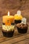 Halloween cupcakes and a burning candle on an old rustic wooden table
