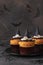 Halloween cupcakes decorated witch hat from mastic on brown background with spiders and bats, sweets for kids on