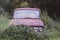 Halloween decoration on the old car in wild nettle bushes. Orange paper pumpkin decor outdoors