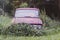 Halloween decoration on the old rusty car in nettle bushes. Orange paper pumpkin decor outdoors