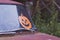 Halloween decoration on the rusty car in wild nettle bushes. Orange paper pumpkin decor outdoors