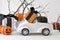 Halloween decorations. Close up retro toy car with pumpkins, gifts over tree branches. Creepy and funny concept.