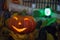 Halloween decorations concept at night. Close up of jack o`lantern, vintage lanterns, pumpkins, skull, autumn leaves