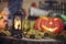 Halloween decorations concept at night. Close up of jack o`lantern, vintage lanterns, pumpkins, skull, autumn leaves