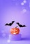 Halloween decorations with pumpkin on podium, spider and bat on purple background. Halloween party concept.