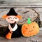 Halloween felt witch doll and pumpkin head near the stump. Wooden background