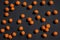 Halloween festive background. Randomly scattered orange fluffy pom-poms on a black background. Top view. Copy space