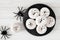 Halloween ghost donuts, above view with spiders over white wood