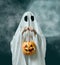 Halloween ghost holding pumpkin basket with candy.