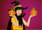 Halloween. A happy woman in a hat and a witch costume holds a pumpkins