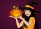 Halloween. A happy woman in a hat and a witch costume holds a pumpkins