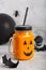 Halloween healthy pumpkin or carrot drink in the glass jar with scary face on a gray background