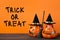 Halloween holiday background with jack lanterns pumpkin, broom and witch hat on wooden table