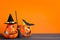 Halloween holiday background with jack lanterns pumpkin, broom and witch hat on wooden table.