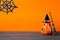 Halloween holiday background with jack lanterns pumpkin, broom and witch hat on wooden table.