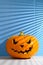 Halloween holiday background. Spooky Halloween pumpkin on a pastel blue background, illuminated by sunlight through the