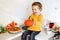 Halloween holiday , child girl on the kitchen with pumpkin in hands and decorations on the table