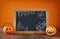 Halloween holiday concept. Cute pumpkins next to blackboard,