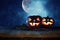 Halloween holiday concept. Empty rustic table in front of Pumpkins over wooden table at night scary, haunted and misty forest. Rea