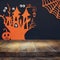 Halloween holiday concept. Empty rustic table in front of witch house and pumpkin background. Ready for product display montage.