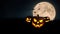Halloween holidays wallpaper with free space for text and design. . Pumpkins glow in a field of grass with a scary full moon and