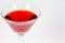 Halloween inspired blood red color cocktail in a clear glass sitting on a white table waiting to be enjoyed.